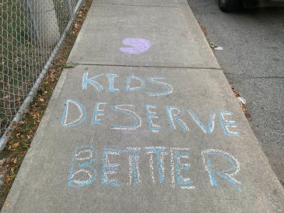 Chalk drawing of text 'Kids Deserve Better'